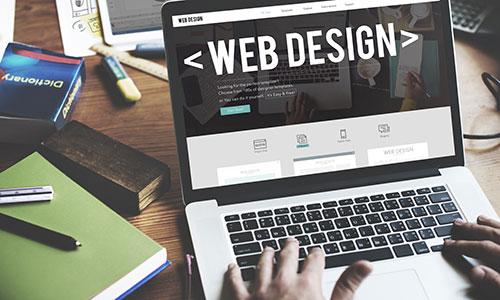 Person arbeitet an einem Laptop mit geöffneter Webdesign-Software.